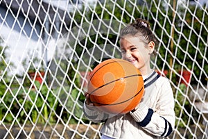 Close up of a little girl smiling with a basketball, vertical photo