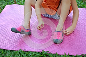 Close-up little girl tries to put on her shoes outdoor