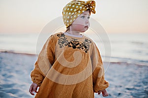 Close-up of little girl walking along the beach at sunrise