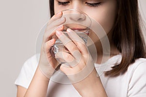 Close up little healthy girl drinking glass of pure water.
