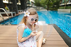 close up little kid sitting close to swimming pool wearing sungl