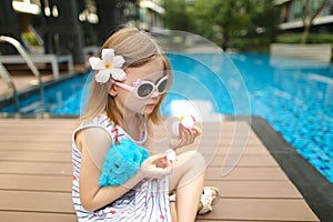 Close up little kid sitting close to swimming pool wearing sungl