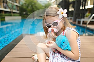 Close up little kid sitting close to swimming pool wearing sungl