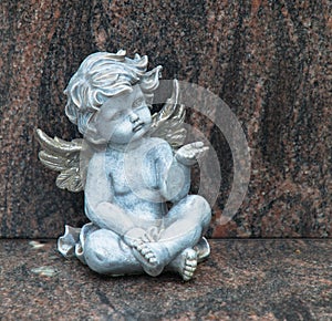 Cemetery scene. Close up of a sad pensive angel sitting on a grave. Pain, fear, end of life