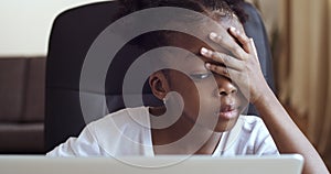 Close-up little sad mixed race afro american girl child sitting in front of laptop suffers from learning difficulties