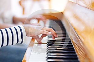 Close up of a little student`s hands is playing piano