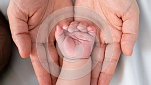 Close up little tiny baby hand palm over a mother hands. Peace calm newborn