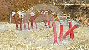 CLOSE UP: Long red plastic conduits stick up in the air from the gravel ground