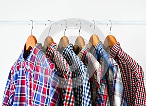 Close up long sleeve red and blue checkered shirt on wooden hanger on white color rack over white background with copy space