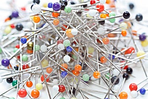 Close up of loose multicolored sewing pins on white background