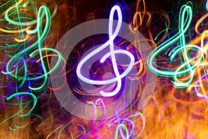 Close-up lot of multicolored neon glowing treble clefs. Abstract  luminous background