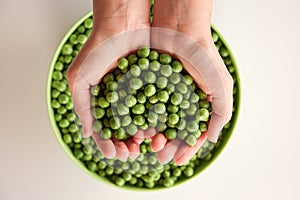 Close-up of a lot of ripe peas in hands, heart shaped. Green pea in a green bowl. Tasty and healthy food. Vegetables