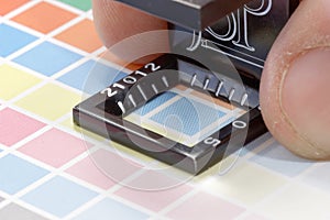 Close-up of a loupe and hand on a colorful test print