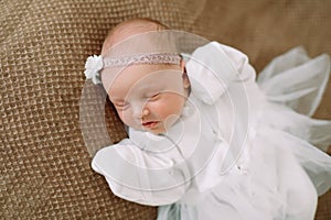 Close-up lovely newborn baby girl on a blanket. A portrait of a beautiful  newborn baby girl wearing a headband. Closeup photo