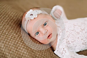 Close-up lovely newborn baby girl on a blanket. A portrait of a beautiful  newborn baby girl wearing a headband. Closeup photo