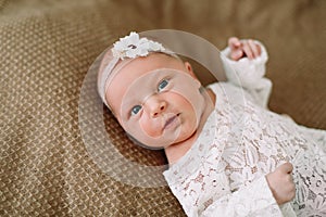 Close-up lovely newborn baby girl on a blanket. A portrait of a beautiful  newborn baby girl wearing a headband. Closeup photo