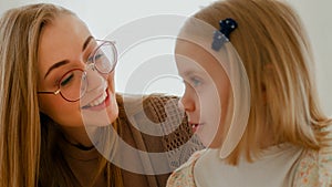 Close up loving Caucasian mom mother in glasses talking to little 6s daughter speaking together indoors. Preschool kid