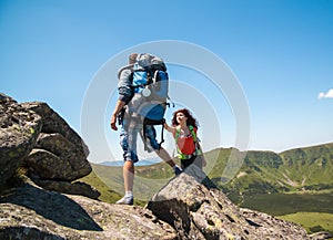 Close-up of loving couple hikers climbing up on the peak of mountain. Climbing, Helps and Team work concept