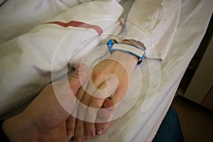 Close up of loving couple holding hands on hospital bed, showing care and love