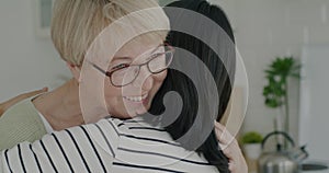 Close-up of loving daughter hugging elderly mother expressing love and talking to senior woman at home