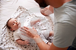 Close Up Of Loving Father Lying With Newborn Baby On Bed At Home In Loft Apartment