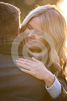 Close Up Of Loving Newly Engaged Couple Hugging On Walk In Winter Countryside With Lens Flare