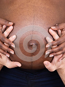 Close up of loving pregnant couple hands on belly white and black mixed race