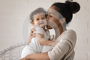 Close up loving young African American mother kissing toddler daughter