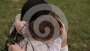 Close-up loving young mother hugging, calming little son who is crying outdoors