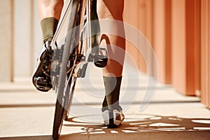 Close up, low angle view on a bike, back wheel on foreground. Man& x27;s legs riding his bicycle on road in summer