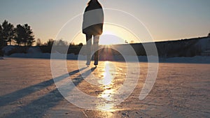 CLOSE UP, LOW ANGLE VIEW: Happy woman iceskating fast on frozen pond in local park at golden sunset on magical Christmas