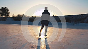 CLOSE UP, LOW ANGLE VIEW: Happy woman iceskating fast on frozen pond in local park at golden sunset on magical Christmas