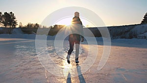 CLOSE UP, LOW ANGLE VIEW: Happy woman iceskating fast on frozen pond in local park at golden sunset on magical Christmas