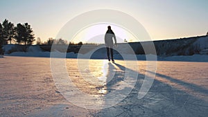 CLOSE UP, LOW ANGLE VIEW: Happy woman iceskating fast on frozen pond in local park at golden sunset on magical Christmas