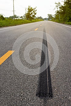 A close-up low-angle view. A long line of black rubber tires stopping violently against the paved road surface