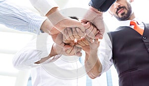 Close up low angle view of young business people putting their hands together. Stack of hands. Unity and teamwork concept