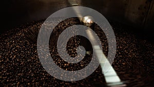 Close-up and low speed shutter blurred to capture the movement of dark roast coffee bean moving in rotating mixing coffee roaster