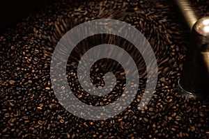 Close-up and low speed shutter blurred to capture the movement of dark roast coffee bean moving in rotating mixing coffee roaster