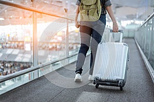 Close up lower body of woman traveler with luggage suitcase going to around the world by plane. Female tourist escalator