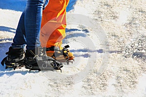 Close up of lower legs of two travelers starting climb to glacier. Feet of couple in love in shoes crampons on glacial trail.