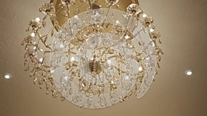 Close-up of luxurious ceiling shade hanging in high class hotel. Bright golden lampshade in accommodations indoors