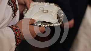 Close up of luxurious rings on plate in the church. Wedding ceremony