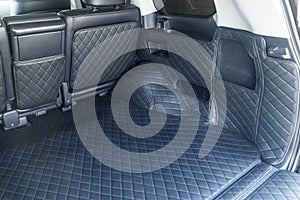 Close-up luxury leather interior trim with white diamond stitching. Stitching of the car trunk trim. Car interior
