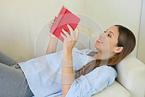 Close up of lying woman reading book relaxing on sofa at home