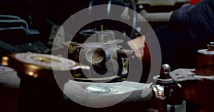 Close-up of a machine engine. a man`s hand in a black glove is doing something out of focus in the background