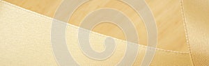 Close up macro antique golden light silk fabric ribbon on wood texture  smooth wave curve abstract background with empty space.