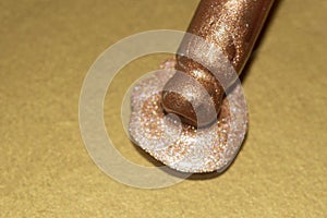 Close up macro of bronz highlighter pippete on a gold background