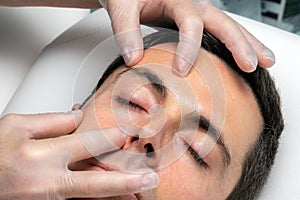 Hands with medical exam gloves inspecting eyelid of middle aged man