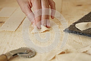 Close up macro detail of process of homemade vegan farfalle pasta with durum wheat flour. The cook kneads the dough on the wooden