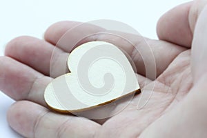 Close up macro man hand holding wooden heart, love symbol on white background